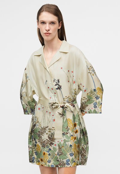 Robe à motif floral en tissu beige clair, avec un col à revers, des manches courtes et une taille cintrée par une ceinture. Accents de vert et de jaune.
