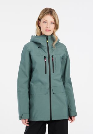 Grüne wasserdichte Jacke mit Kapuze, ausgestattet mit Reißverschlusstaschen, schwarzen Akzenten und einer lockeren Passform. Texturiertes Material für Langlebigkeit.