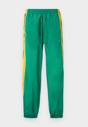 Zelene nylon hlače za tek s rumenimi bočnimi črtami, elastičnim pasom z vrvico za zategovanje in elastičnimi manšetami na gležnjih.