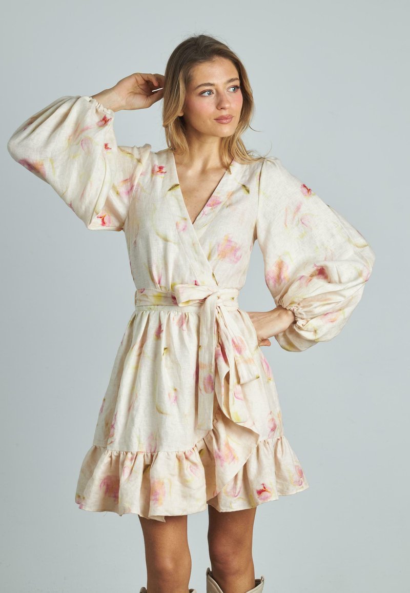 Blumenkleid aus hellbeigem Stoff mit rosa und grünen Akzenten. Verfügt über voluminöse Ärmel, eine gebundene Taille und einen rüschierten Saum.