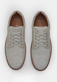 Scarpe in suede grigio con design perforato, dotate di sei fori per i lacci, lacci grigi e suole in legno marrone. La fodera presenta una texture di pelle liscia.