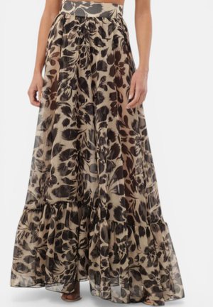 Gonna lunga e fluida con vita ampia, con motivo floreale nero e marrone su tessuto beige, indossata da una persona in piedi.