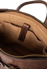 Brązowa skórzana torebka z beżową tkaniną wewnętrzną, zamykana na zamek, z wewnętrzną kieszonką zabezpieczoną skórzanym paskiem.