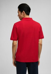 Rode polo met een klassieke kraag, korte mouwen en een rechte zoom. Effen textuur en minimalistisch ontwerp.