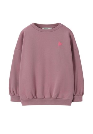 Enfant aux longs cheveux tressés portant un sweat-shirt rose avec le texte "NEVER NOT DANCING" en lettres majuscules au dos.