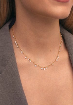 Collana in oro con gocce di cristallo trasparente, caratterizzata da un design delicato e lunghezze alternate di cristalli lungo la catena.