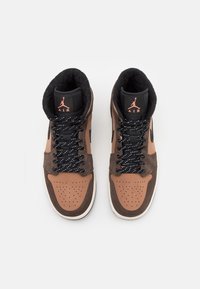 Paire de baskets montantes Air Jordan marron et marron foncé avec des lacets noirs et blancs, vue de dessus sur fond blanc.