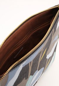 Torba w wzór kwiatowy z teksturowaną powierzchnią, z brązowym wnętrzem, zamknięciem na zamek błyskawiczny oraz wieloma wewnętrznymi kieszeniami do organizacji.