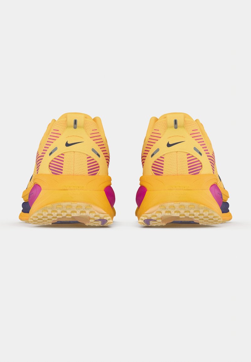 Zapatillas de running Nike con parte superior amarilla, acentos morados, patrones a rayas y una suela texturizada para tracción. Vista trasera que muestra los detalles del diseño.