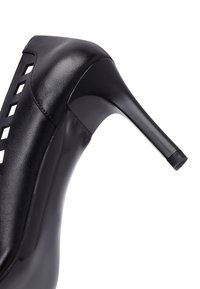 Chaussure à talon haut noire au design épuré, avec une tige en cuir lisse, des découpes décoratives et un bout pointu.
