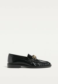 Svarta läderloafers med en sömnaddesign, platåklack och en guldfärgad hårdvaruaccent framtill. Slät, blank yta.