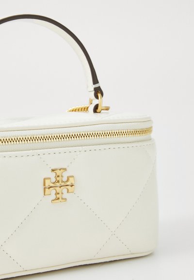 Bijela torba od quiltane kože s zlatnim detaljima i zatvaranjem na zip. Uključuje smeđu dršku i ima brendirani emblem na prednjoj strani.