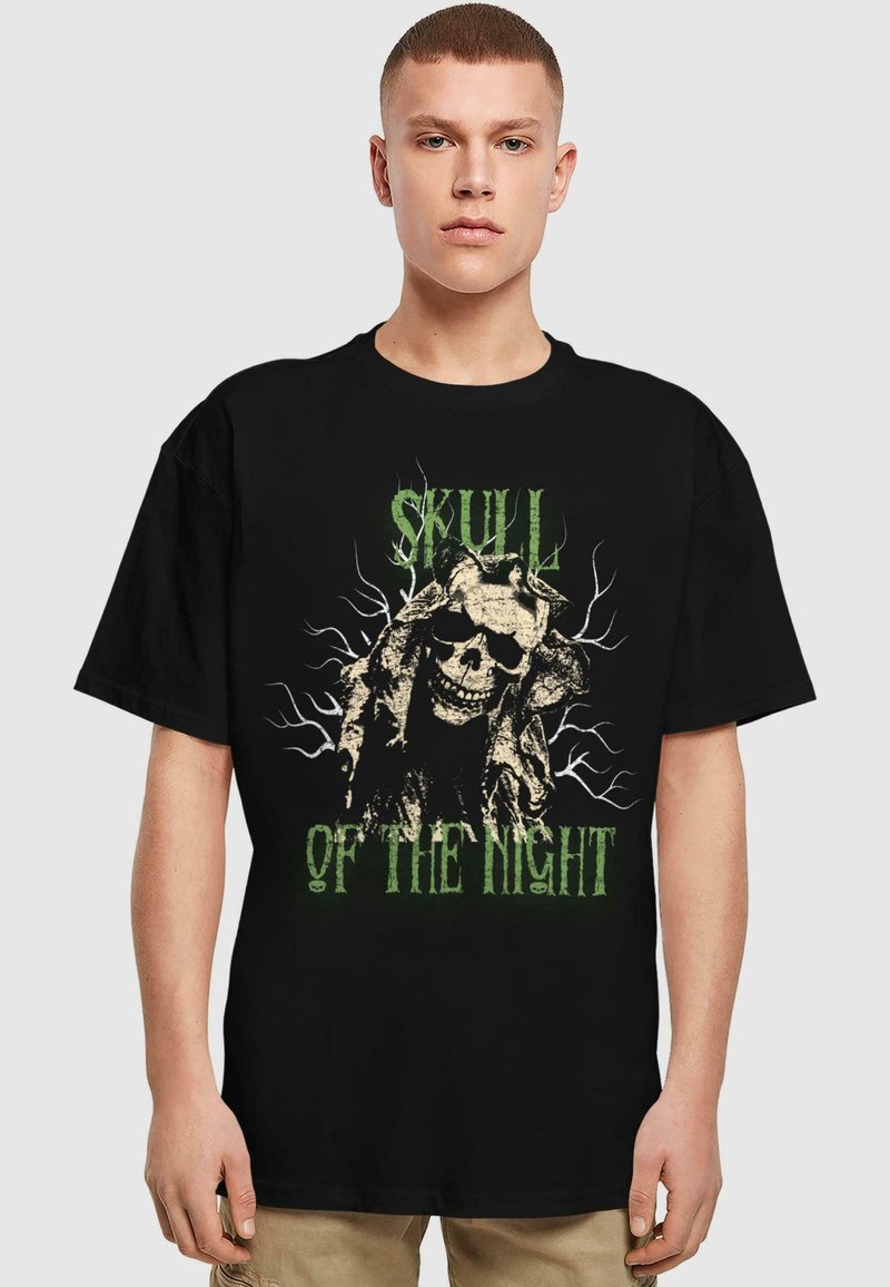 Sort t-shirt med et kranie-design og grøn tekst, der står "SKULL OF THE NIGHT", omgivet af intrikate grenmønstre.