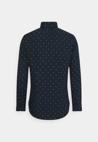 Camicia a maniche lunghe in tessuto blu navy scuro con motivi a diamante bianchi, colletto a punta e polsini con bottoni. La vista posteriore mostra un orlo curvo.