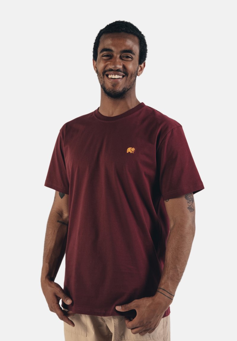 Bordeauxrotes Baumwoll-T-Shirt mit kurzen Ärmeln und rundem Ausschnitt, das auf der linken Brust ein kleines gesticktes Elefantenlogo in Orange zeigt.