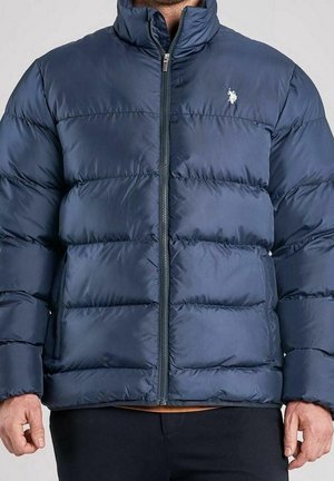 Marineblaue gesteppte Jacke mit durchgehendem Frontreißverschluss, getragen von einer Person, mit kleinem weißem gesticktem Logo auf der linken Brust.