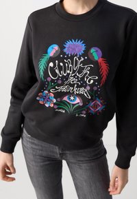 Sudadera negra con un estampado gráfico colorido que presenta formas abstractas y el texto "Club de los Pensadores Libres." Cuello redondo clásico y puños acanalados.