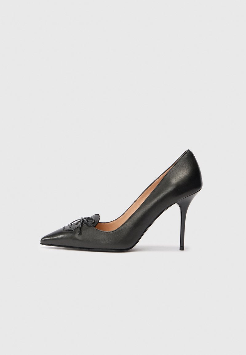 Must musta terava varvas, kõrge konts, õhuke stiletto konts ja väike dekoratiivne pael esiplaanil.