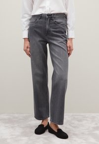 Grijze denim jeans met een relaxte pasvorm, hoge taille, vijf zakken en een licht vervaagde afwerking, gecombineerd met zwarte instappers.