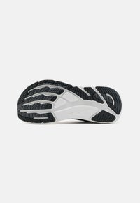 Black and white athletic shoe sole, featuring a textured rubber surface, distinct grooves, and a sleek, streamlined design.