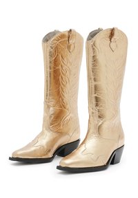 Arany színű fémes cowboy csizmák hímzett láng mintákkal, hegyes orral és alacsony blokksarkakkal. Simább felület és díszítő varrás.
