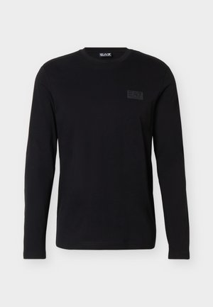 Črna majica z dolgimi rokavi in okroglim izrezom, z diskretno oznako z logotipom EA7 na zgornjem levi strani prsi, prikazana na belem ozadju.