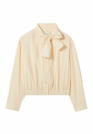 Blusa de color durazno claro con un lazo en el cuello, mangas largas, frente abotonado y dobladillo con elástico recogido. Tela suave y lisa, diseño minimalista.