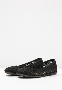 Ballerine in pizzo nero con un motivo testurizzato, punta tonda e apertura elasticizzata per una vestibilità sicura. Suola piatta in gomma per il massimo comfort.