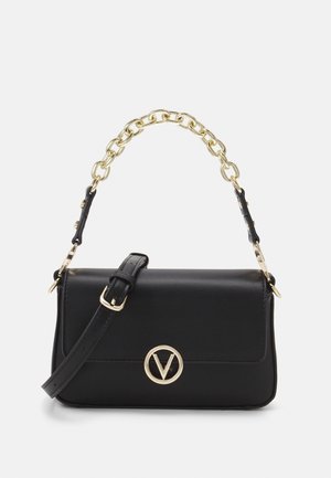 Bolso de piel negra con una cadena dorada y un logotipo circular dorado. Presenta un cierre de solapa y una correa para el hombro ajustable.