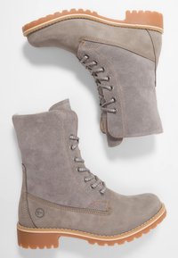 Stivaletti alla caviglia in suede grigio con finitura testurizzata, hardware argentato e suole in gomma tan a contrasto. Presentano lacci sul davanti.