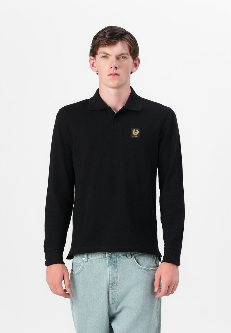 Pikemate musta polo-särgid, pikad varrukad ja krae, vasakul rinnal kuldne embleem. Valmistatud siledast kangast; lõdva istuvusega ning ribadega mansettidega.