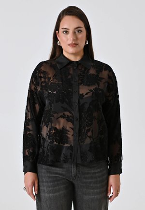 Black sheer blouse with floral embroidery, long sleeves, button front, and classic collar. Textured fabric contrasts with solid cuffs.