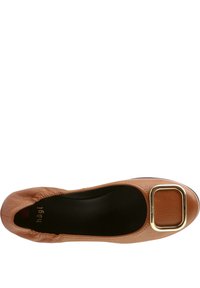 Ballerines en cuir beige avec un bout rond, mettant en avant une pince rectangulaire dorée sur l'empeigne et une doublure intérieure noire.