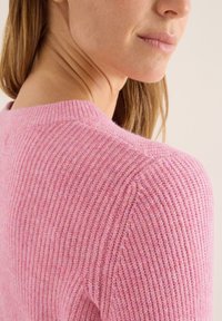 Różowy sweter z prążkowanym wzorem, z okrągłym dekoltem i miękką teksturą, z naciskiem na wzór dzianiny i detale na ramionach.
