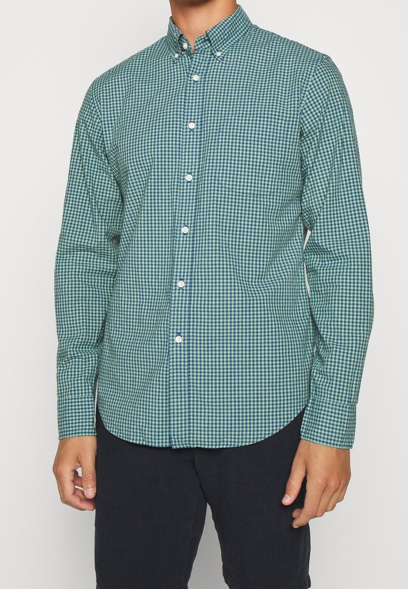 Grün-blau kariertes Hemd mit Knöpfen, Kragen, langen Ärmeln und abgerundetem Saum. Hergestellt aus leichtem Stoff mit weicher Textur.