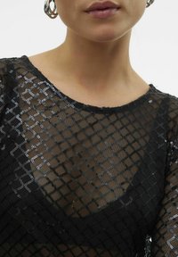 Schwarzes Netzoberteil mit einem Gittermuster, das silberne Akzente aufweist. Rundhalsausschnitt und durchscheinende Textur, die die Haut darunter betont.
