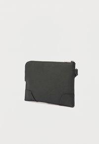 Fekete bőrből készült erszény texturált felülettel, cipzáras záródással és oldalsó fogantyúval. Minimalista kialakítás és sima élek jellemzik.