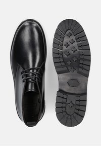 Zwarte leren enkellaarzen met veters, voorzien van een gestructureerde zwarte rubberen zool met een patroon voor grip.