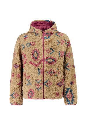 Vrouw die een gemêleerd beige fleecejack draagt, felroze broek, roze zonnebril en een roze-beige muts, staand tegen een effen achtergrond.