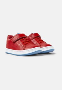 Chaussures pour tout-petits en cuir rouge avec une finition texturée, dotées d'une sangle velcro, de lacets oranges et d'une semelle en caoutchouc bleue et blanche.