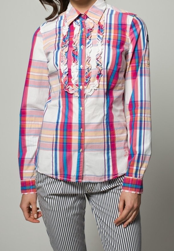 Camicia button-up in una fantasia multicolore a quadri di rosa, blu e giallo, con dettagli arricciati sul davanti e maniche lunghe. Abbinata a pantaloni a righe.