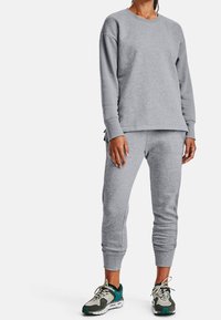 Grå sweatshirt och matchande sweatpants-outfit, tillverkad av mjukt tyg, med långa ärmar, ribbade ärmslut och en avslappnad passform. Sportskor med accenter.
