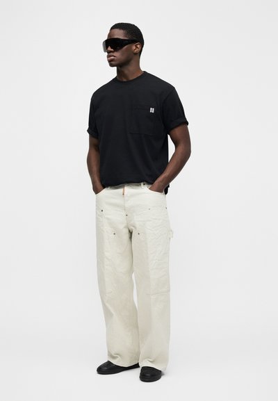 Camiseta negra de manga corta con bolsillo; pantalones blancos ajustados y cónicos; grandes gafas de sol negras; diseño minimalista, textura suave.