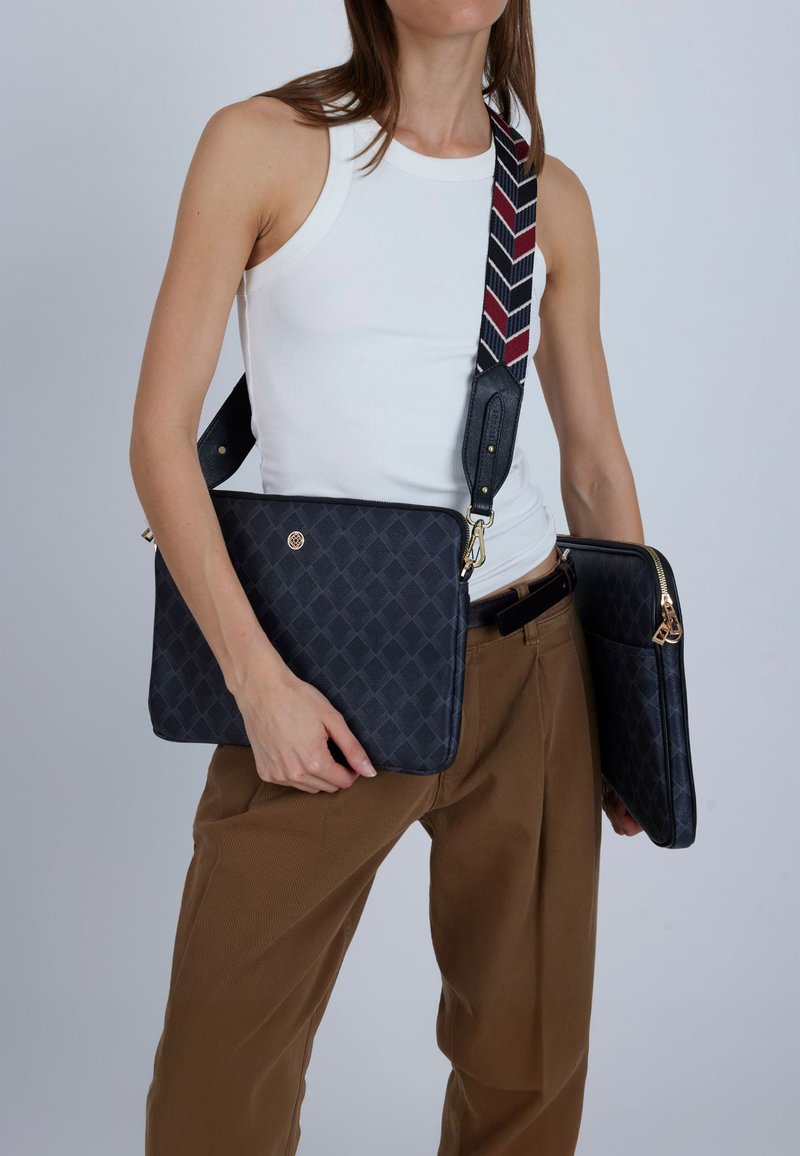 Marinblå messengerväska med geometriskt mönster och justerbar randig rem; fack med dragkedja och guldfärgade detaljer.