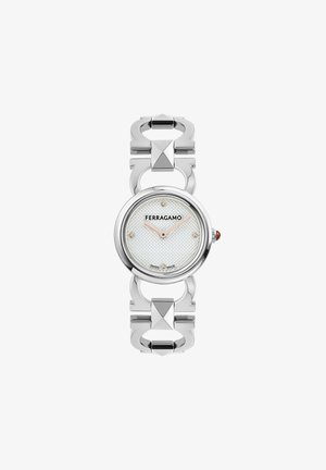 Orologio in metallo argentato con quadrante rotondo bianco texturizzato, logo e accenti di diamanti. Il bracciale presenta forme architettoniche interconnesse.