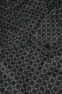 Zwarte stof met een herhalend lichtgrijs bloemmotief met onderling verbonden cirkels. Glad oppervlak met een subtiele glans.