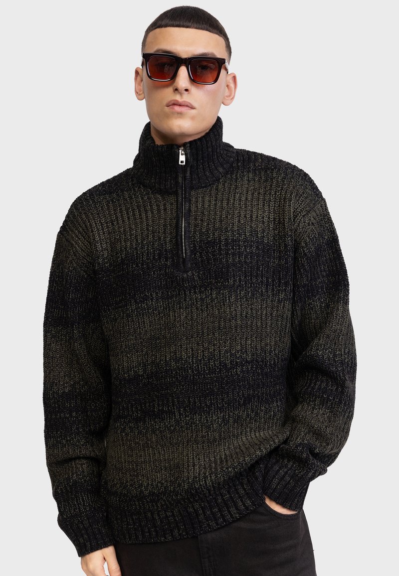 Pull en maille avec col haut, demi-zip, et un motif dégradé allant du vert foncé au noir. Fabriqué avec un fil texturé.