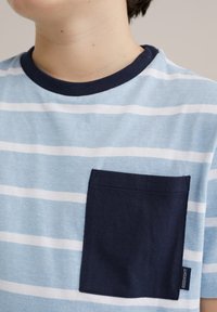 Lichtblauw gestreept T-shirt met horizontale witte strepen, een donker marineblauwe zak en een marineblauwe kraag. Zachte katoen stofstructuur.