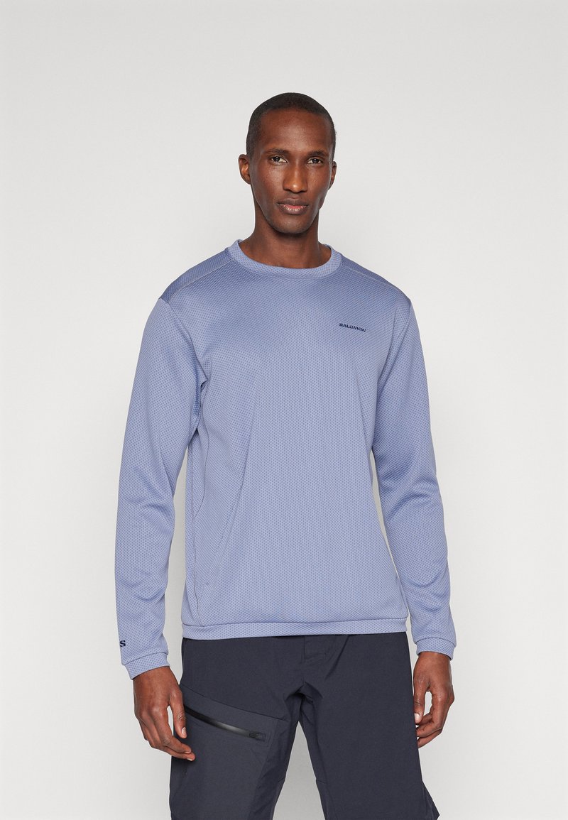 Μακρυμάνικη αθλητική μπλούζα από ανοιχτό μπλε διχτυωτό ύφασμα με στρογγυλή λαιμόκοψη, διαθέτοντας σε αντίθεση πάνελ στους ώμους και δ�ιακριτική σήμανση.