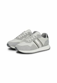 Zapatillas deportivas grises que combinan materiales suaves y texturizados, con detalles a rayas y una suela de goma. Diseño con cordones y acolchado.